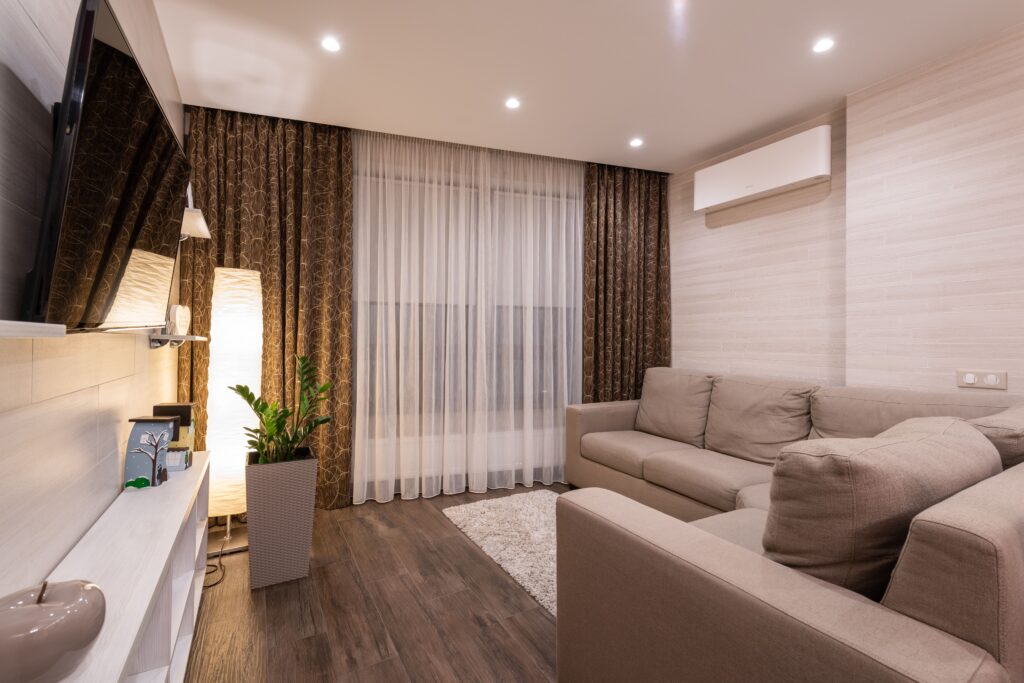 Modern living room with beige sofa and TV.