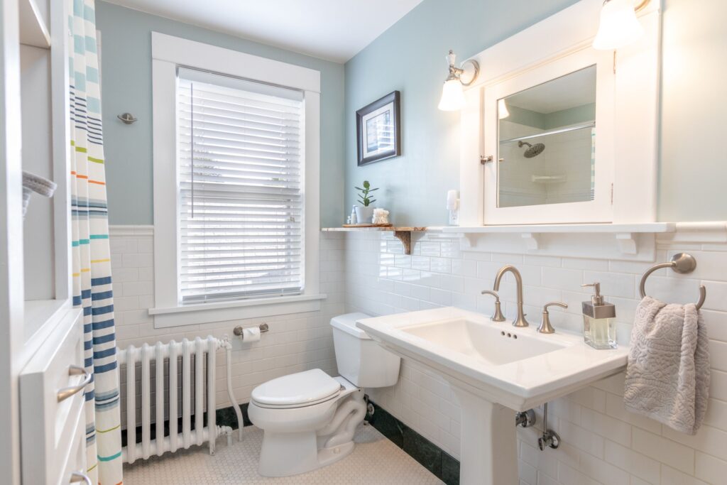 Modern bathroom with sink, toilet, shower, and window.