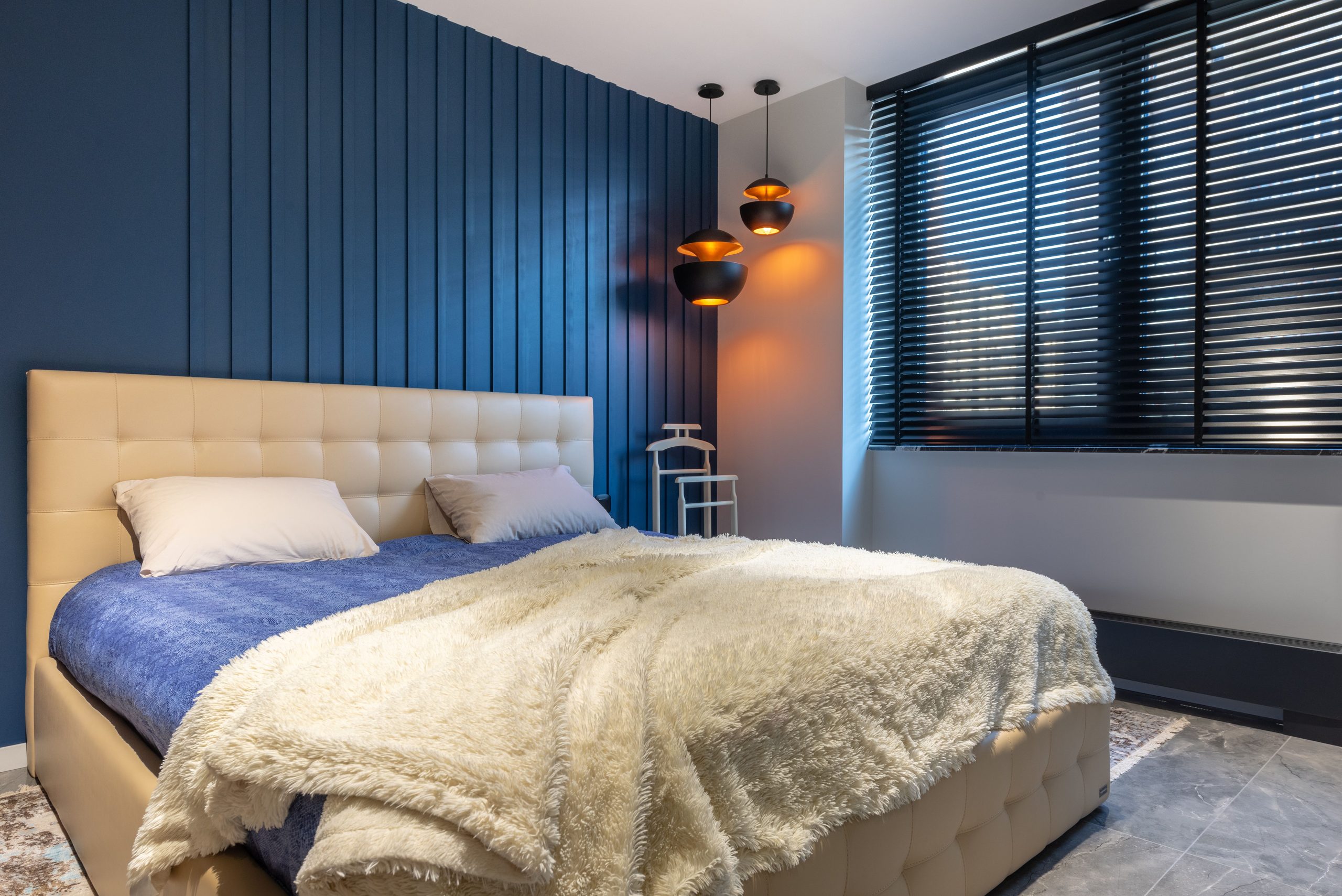 Modern bedroom with blue wall and cozy bed