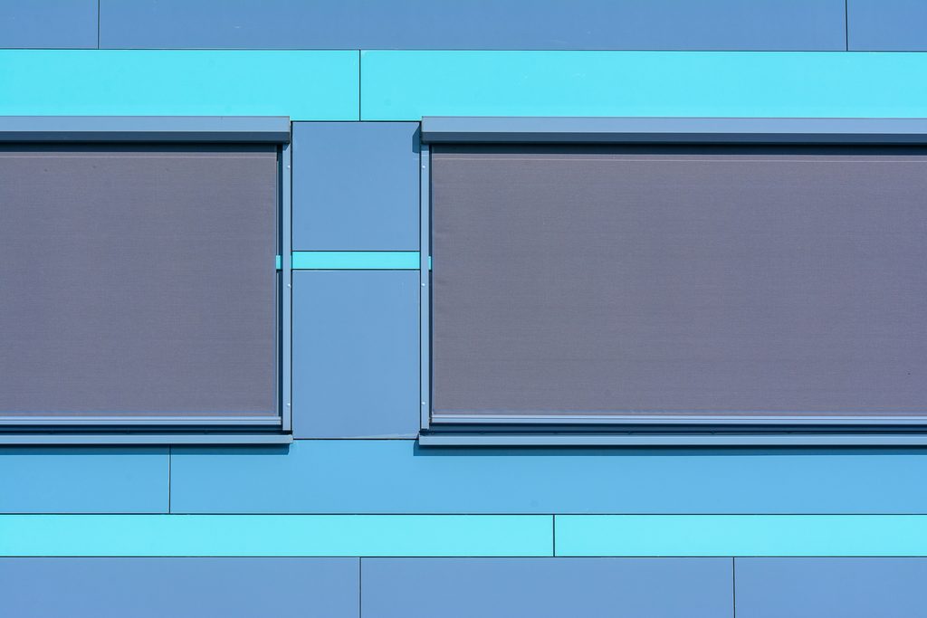 Modern blue wall with two closed windows.