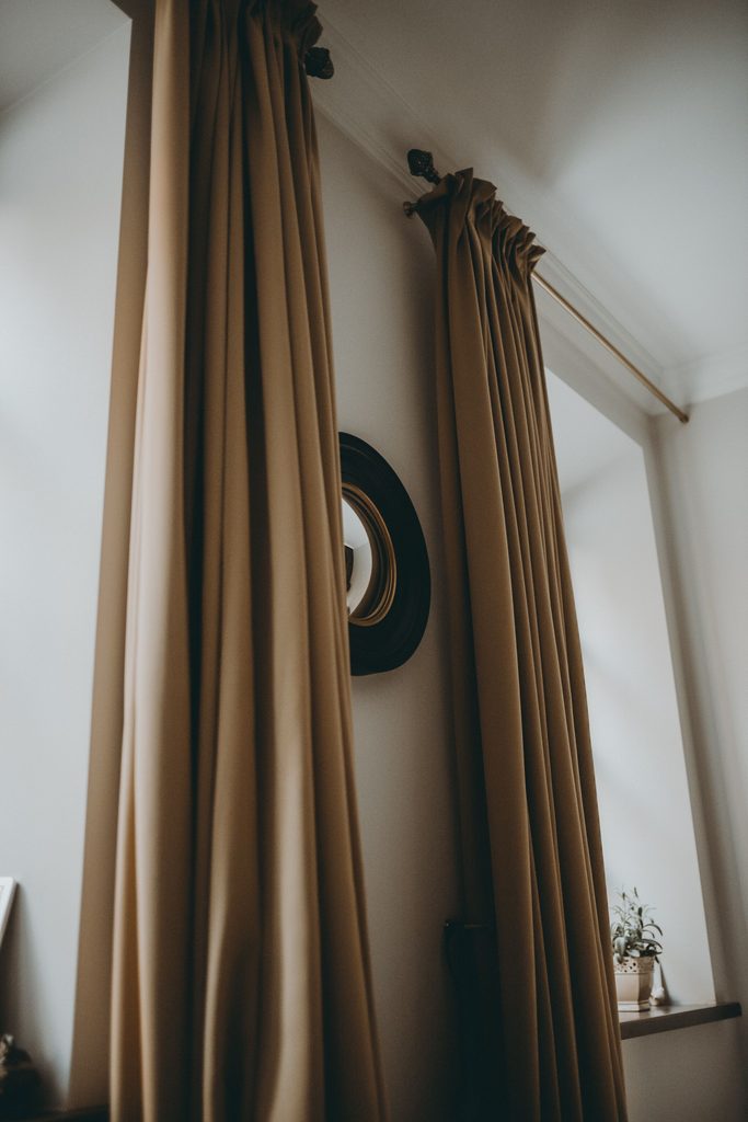Beige curtains beside decorative wall mirror