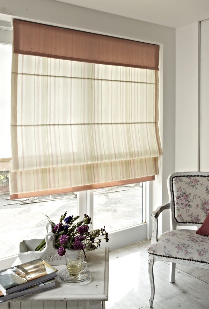 Cozy room with blinds, chair, and flowers.