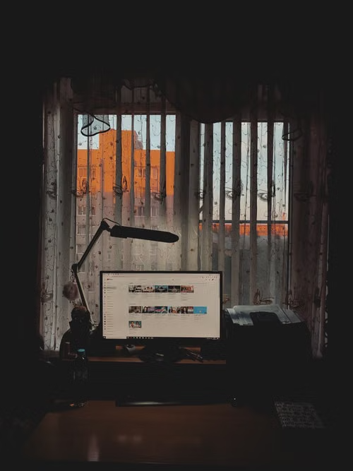 Home office desk with computer and window view.